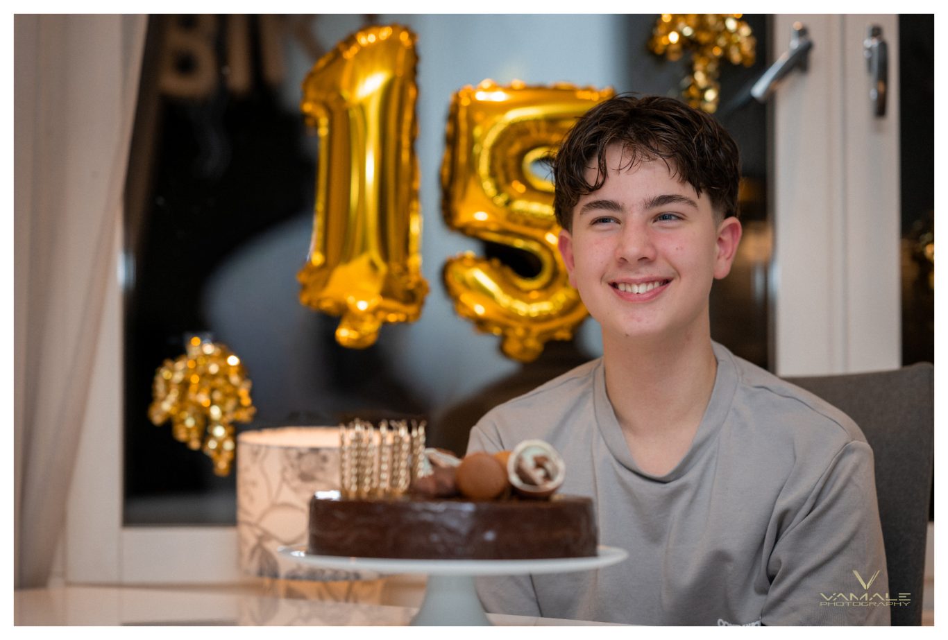 15-åring bredvid tårtan på födelsedagen Femtonåring fotograferad bredvid sin födelsedagstårta, fångad i ett varmt och personligt firande. Foto - Vamale Photography