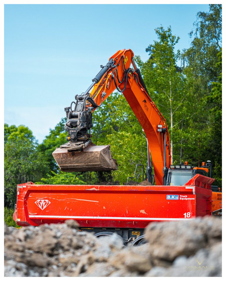 Orange grävmaskin i arbete, kraftfull maskin och tydlig industriell miljö i fokus - Vamale Photography